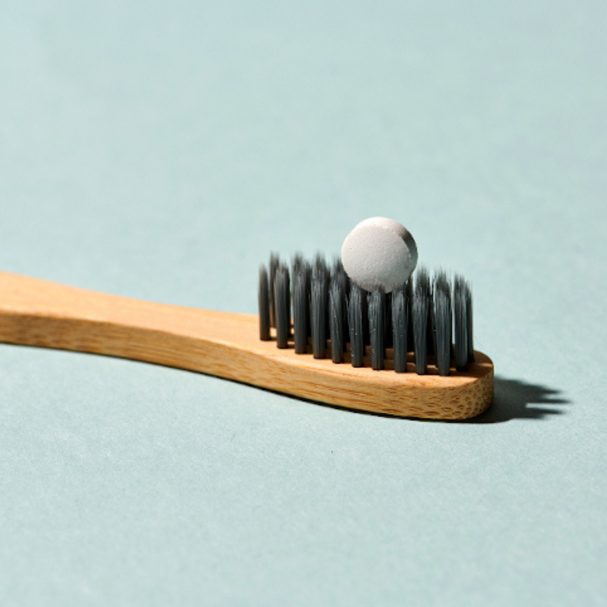 DENTTABS toothpaste tablet on a bamboo toothbrush for plastic-free oral care